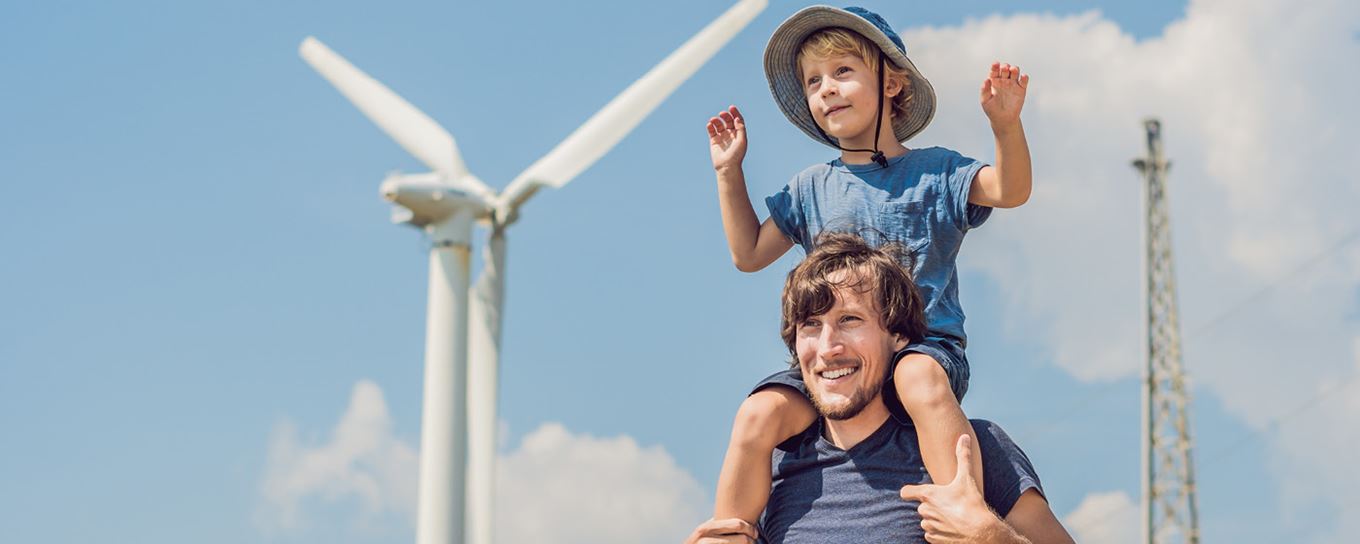 Vader met jong jongetje op zijn schouders bij een windmolen