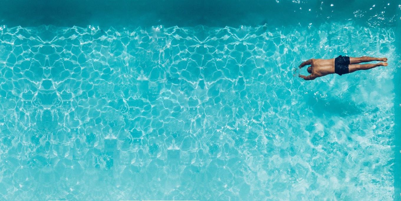 Persoon in zwembroek duikt in buitenzwembad