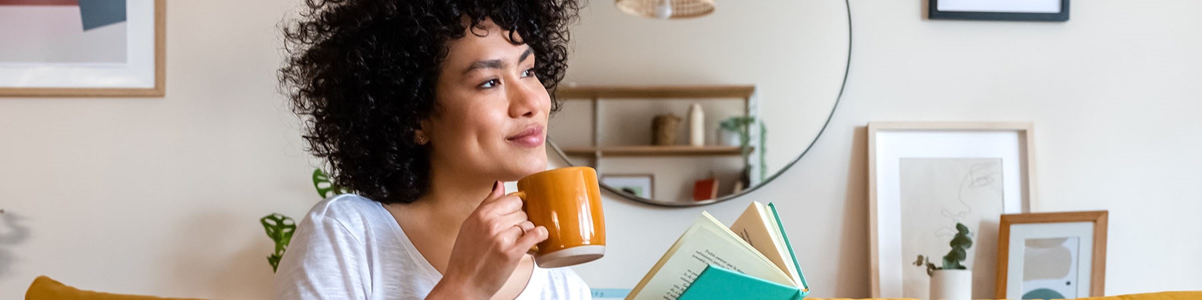 Afbeelding van een vrouw met een boek en een kop koffie in haar handen