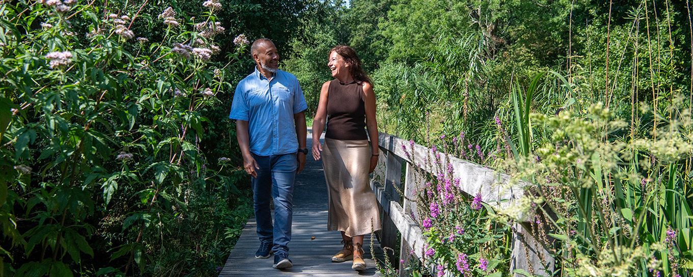 man en vrouw wandelen samen over een bruggetje