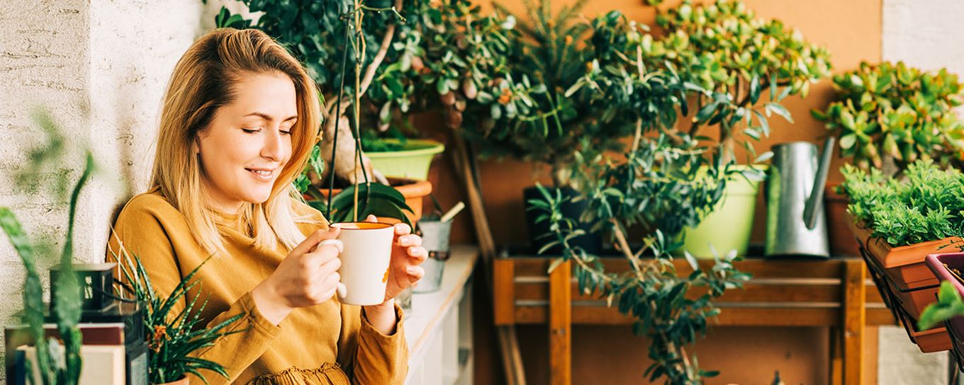 Afbeelding van een vrouw met haar kop thee of koffie zittend op haar balkon