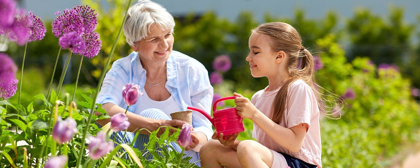 Afbeelding van een oma met haar kleindochter die de plantjes water aan het geven zijn