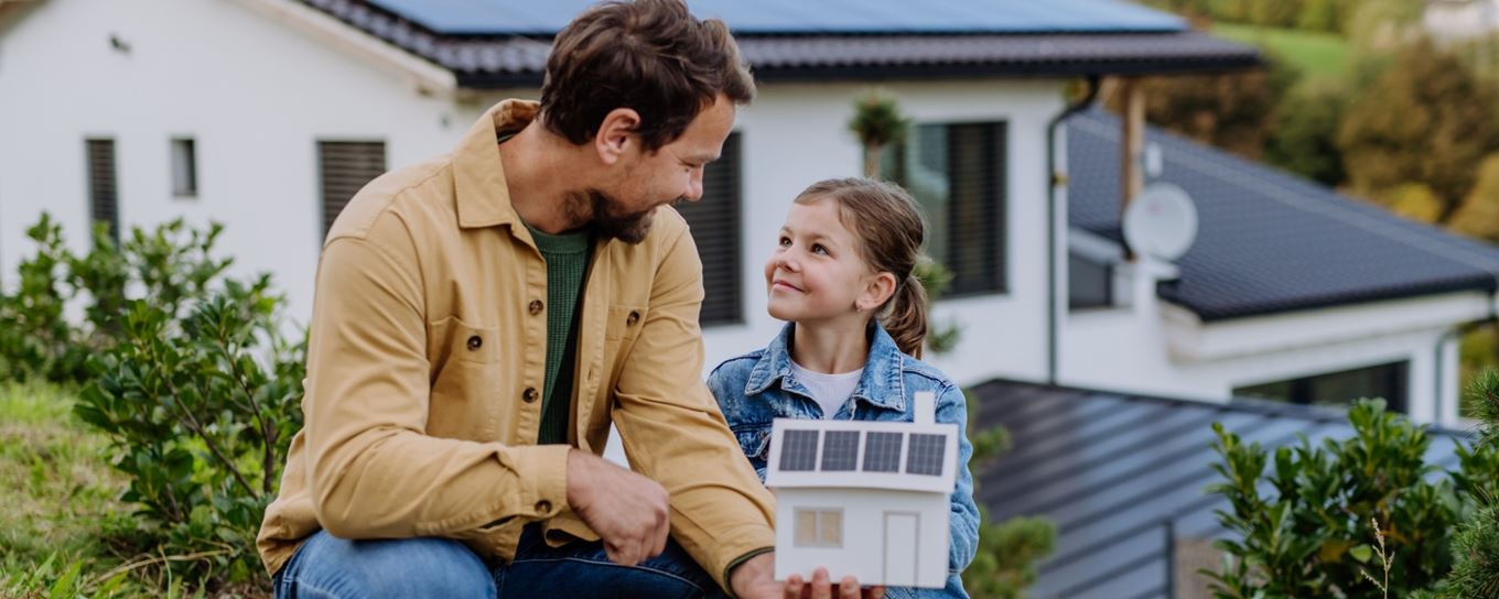 Afbeelding van een man met zijn dochter met een huisje in zijn handen